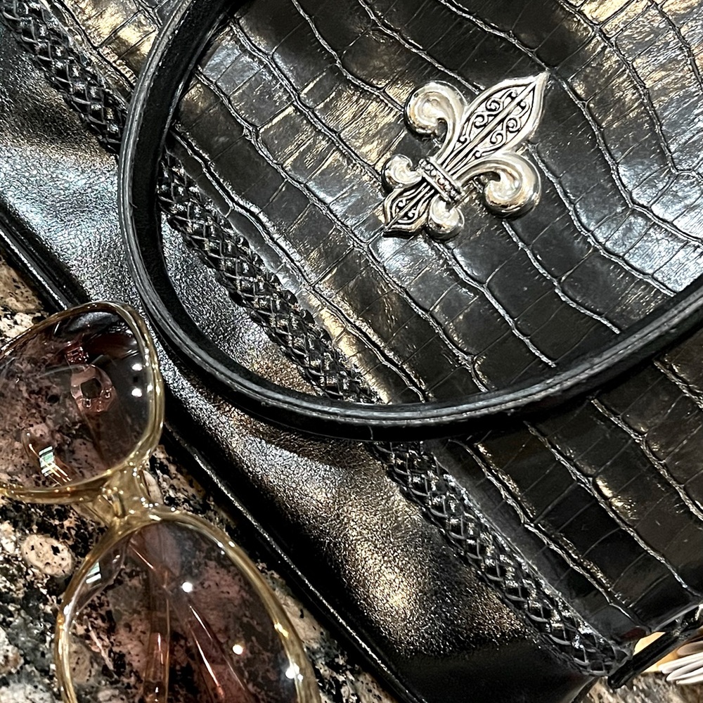 Black purse with handles and Fleur de lis emblem